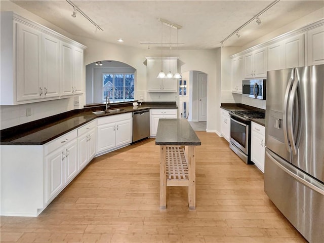 kitchen featuring a sink, dark countertops, appliances with stainless steel finishes, and rail lighting