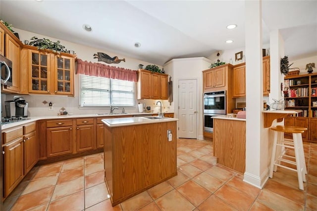 kitchen with a breakfast bar area, stainless steel appliances, a kitchen island with sink, lofted ceiling, and sink