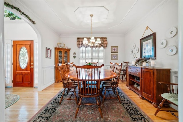 dining room featuring light hardwood / wood-style floors, ornamental molding, and a notable chandelier