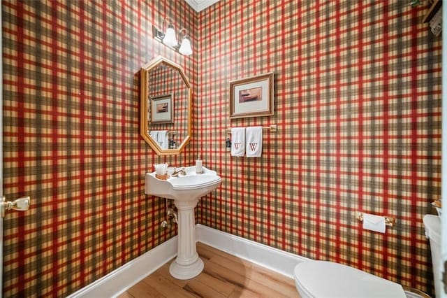 bathroom with toilet, crown molding, and hardwood / wood-style flooring