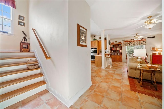 stairway featuring ceiling fan, tile patterned floors, and a healthy amount of sunlight