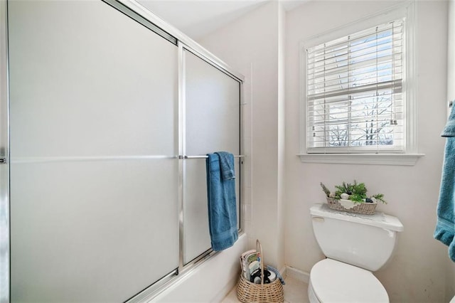 bathroom with toilet, plenty of natural light, and shower / bath combination with glass door