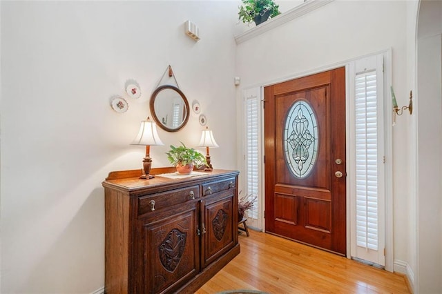 entrance foyer featuring crown molding and light hardwood / wood-style floors