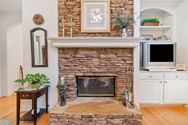 interior details featuring built in features, wood-type flooring, and a stone fireplace