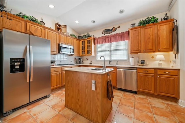 kitchen with stainless steel appliances, sink, a kitchen island with sink, vaulted ceiling, and light tile patterned floors