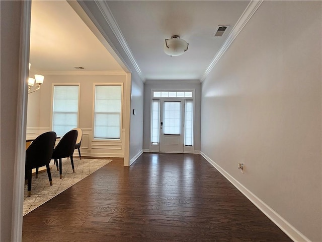 entrance foyer with dark hardwood / wood-style floors, ornamental molding, and a chandelier