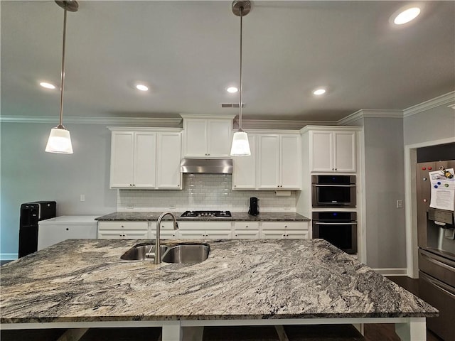 kitchen with pendant lighting, a large island, appliances with stainless steel finishes, and sink