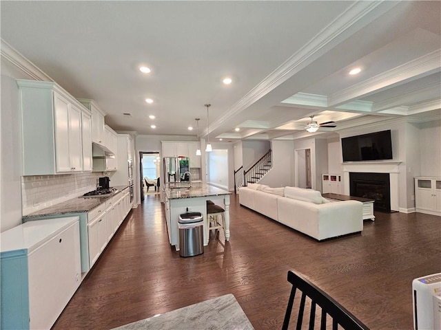 kitchen with white cabinets, a kitchen island with sink, light stone countertops, a kitchen bar, and dark hardwood / wood-style flooring