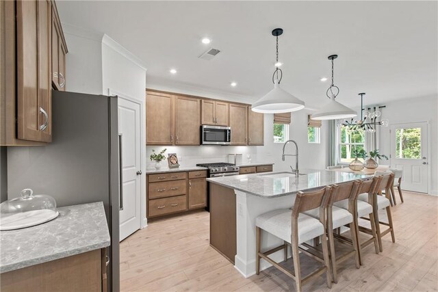 808 Tupelo Way, Villa Rica, GA 30180 - kitchen featuring brown cabinets, appliances with stainless steel finishes, a sink, light wood-style floors, and a kitchen breakfast bar