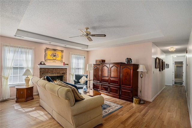 3264 Salem Cove Trl SE, Conyers, GA 30013 - living area featuring a raised ceiling, a textured ceiling, a ceiling fan, light wood-style floors, and a fireplace
