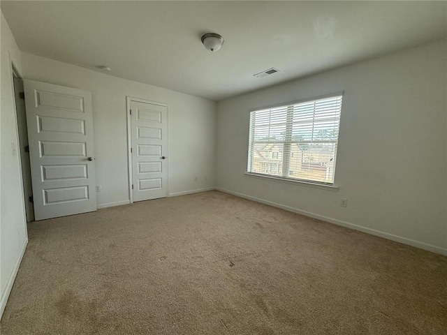 empty room featuring carpet flooring, baseboards, and visible vents