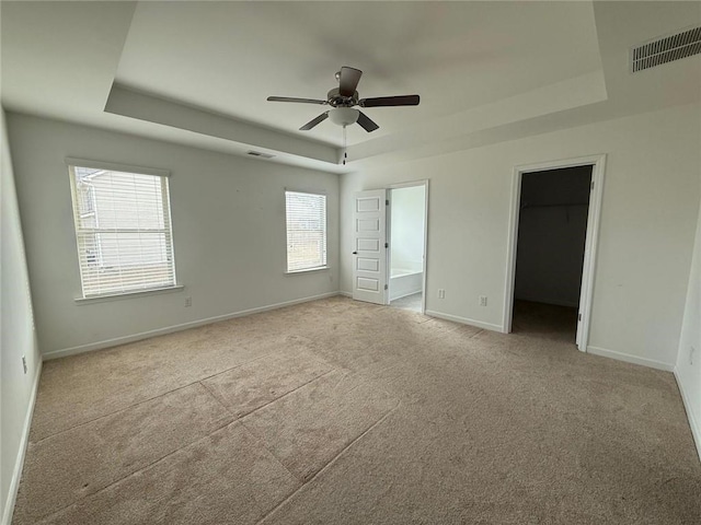 unfurnished bedroom with a tray ceiling, baseboards, and visible vents