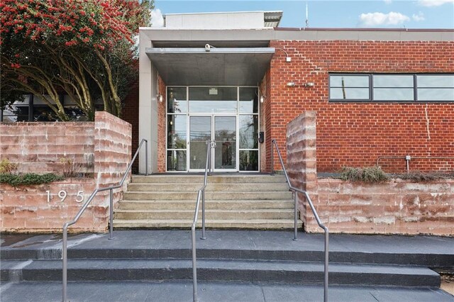 view of exterior entry featuring french doors and brick siding