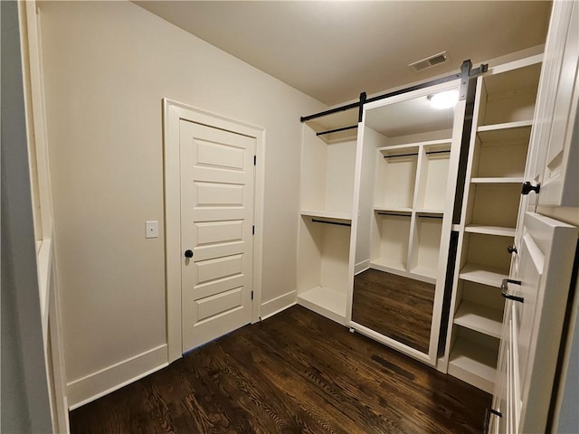 spacious closet featuring dark hardwood / wood-style floors and a barn door