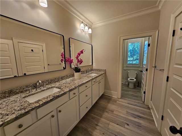 bathroom with toilet, ornamental molding, wood-type flooring, and vanity