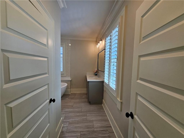 bathroom with vanity, ornamental molding, and a bathing tub