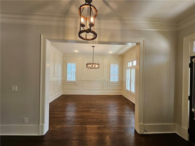 unfurnished dining area with dark wood-type flooring, crown molding, and a chandelier