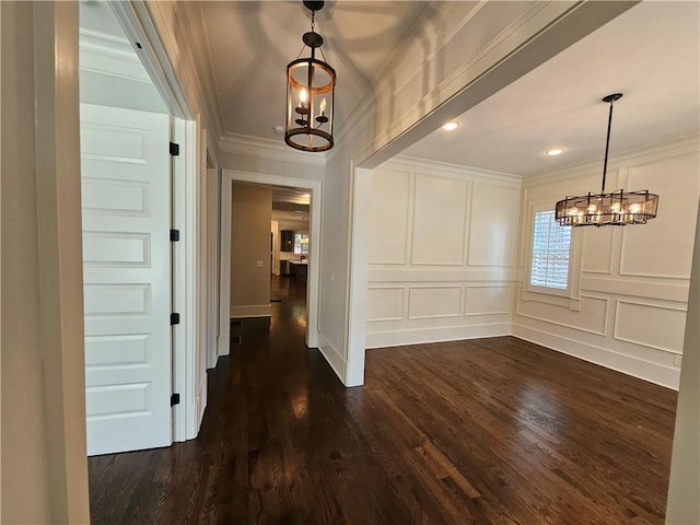 interior space with dark wood-type flooring, ornamental molding, and a notable chandelier