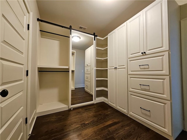 walk in closet featuring a barn door and dark hardwood / wood-style floors