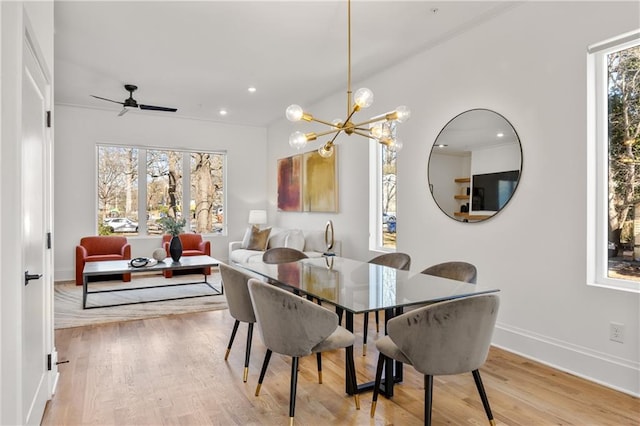 dining space with ceiling fan with notable chandelier and light hardwood / wood-style floors