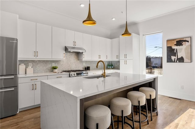 kitchen with sink, stainless steel refrigerator, range, an island with sink, and white cabinets