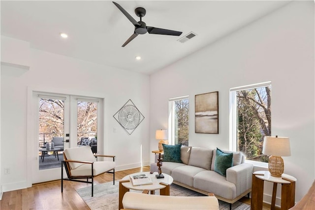 living room featuring french doors, ceiling fan, and light wood-type flooring