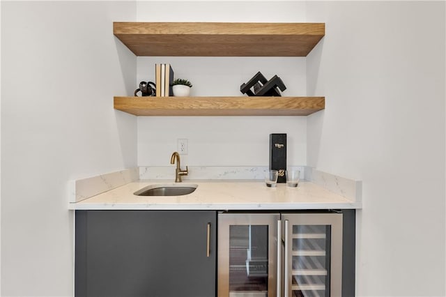 bar with wine cooler, sink, and light stone counters