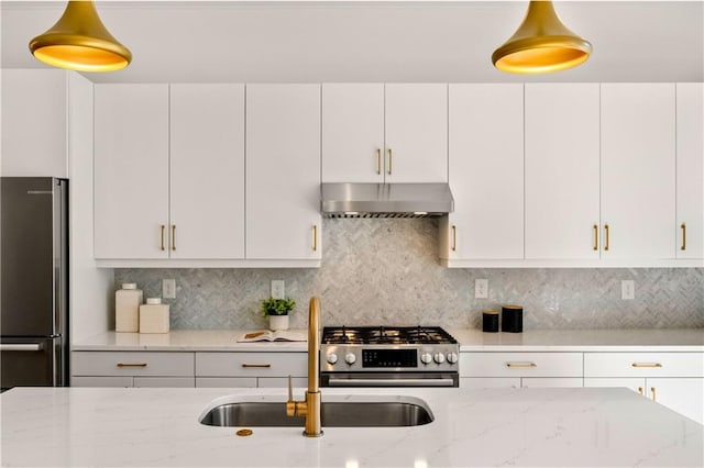 kitchen featuring light stone counters, white cabinetry, appliances with stainless steel finishes, and wall chimney range hood