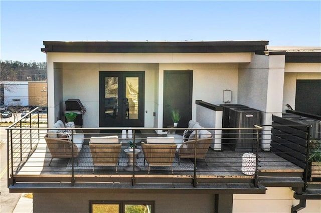 exterior space with a balcony, central AC unit, and french doors