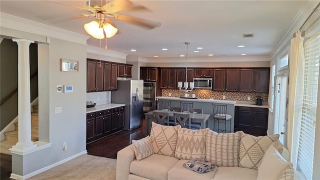 kitchen with stainless steel appliances, visible vents, open floor plan, light countertops, and an island with sink