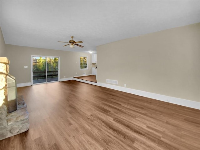 unfurnished living room with ceiling fan, light wood-type flooring, and a fireplace