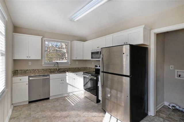 kitchen with appliances with stainless steel finishes, white cabinets, and a wealth of natural light