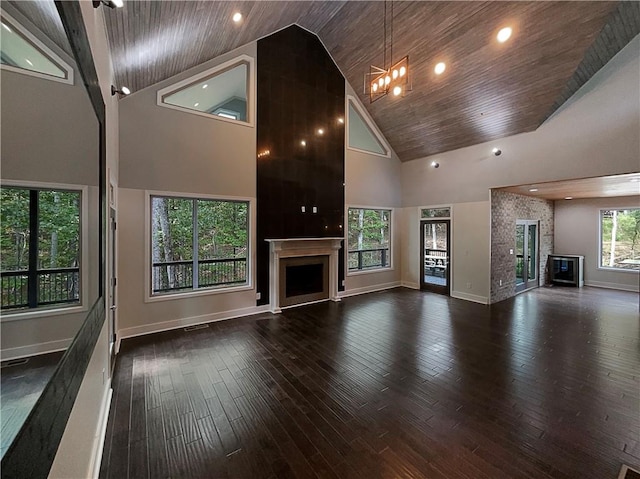 unfurnished living room featuring an inviting chandelier, dark hardwood / wood-style floors, high vaulted ceiling, and wooden ceiling