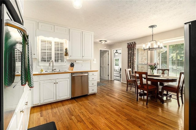5396 Amhurst Dr, Peachtree Corners, GA 30092 - kitchen featuring appliances with stainless steel finishes, a chandelier, a textured ceiling, light wood-type flooring, and white cabinetry
