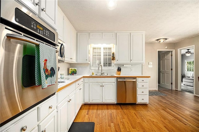5396 Amhurst Dr, Peachtree Corners, GA 30092 - kitchen with appliances with stainless steel finishes, a textured ceiling, white cabinetry, light wood-style floors, and light countertops