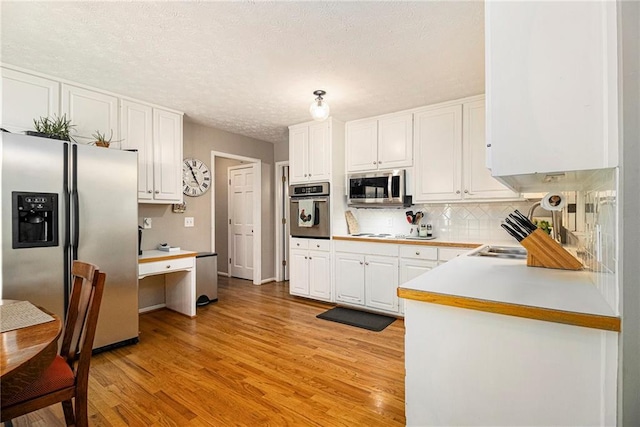 5396 Amhurst Dr, Peachtree Corners, GA 30092 - kitchen featuring stainless steel appliances, white cabinets, light wood-style flooring, decorative backsplash, and light countertops