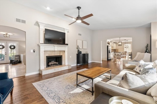 living room with a fireplace, dark hardwood / wood-style floors, ceiling fan, and french doors