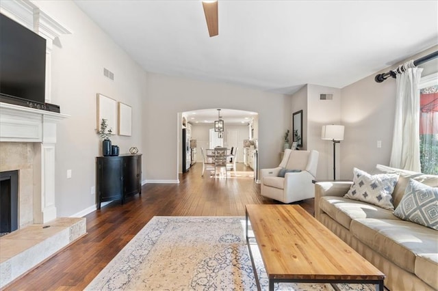 living room featuring vaulted ceiling, dark wood-type flooring, ceiling fan, and a fireplace