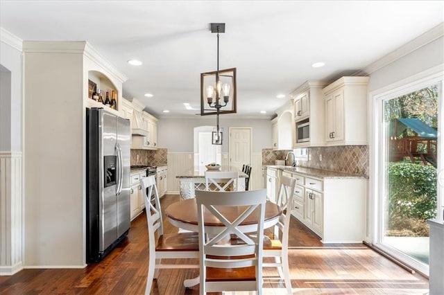 dining area featuring dark wood-type flooring, ornamental molding, a chandelier, and sink