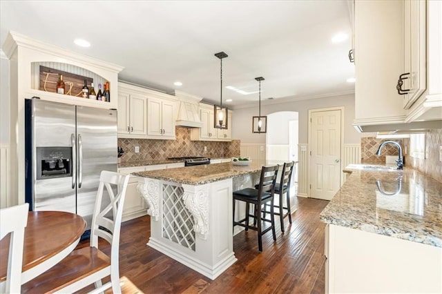 kitchen featuring a kitchen island, appliances with stainless steel finishes, sink, hanging light fixtures, and light stone countertops