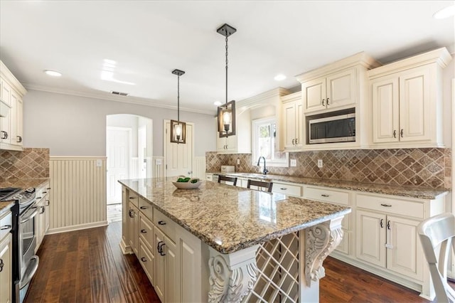 kitchen with light stone counters, decorative light fixtures, stainless steel appliances, and a center island