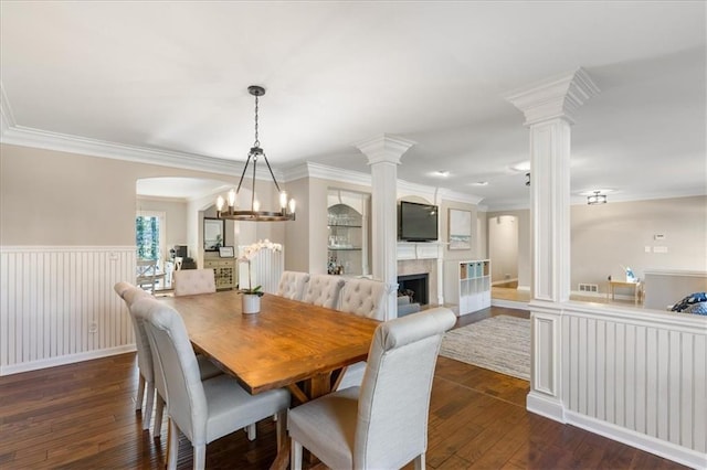 dining room with decorative columns, ornamental molding, and dark wood-type flooring