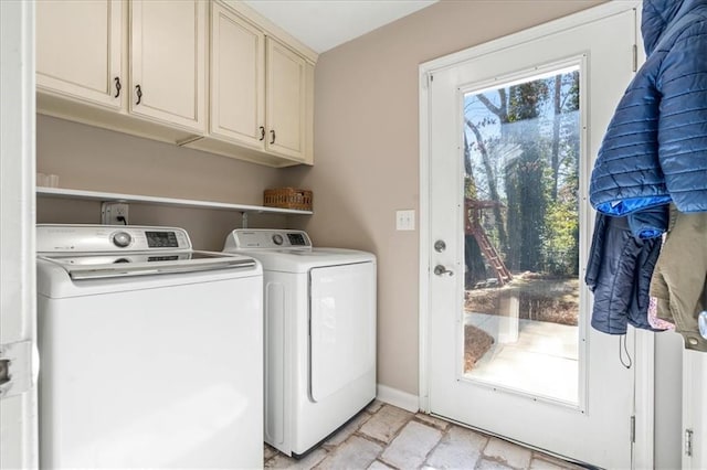 clothes washing area featuring cabinets and washer and clothes dryer