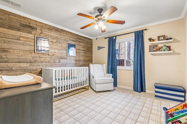 unfurnished bedroom with crown molding, a crib, ceiling fan, and wood walls