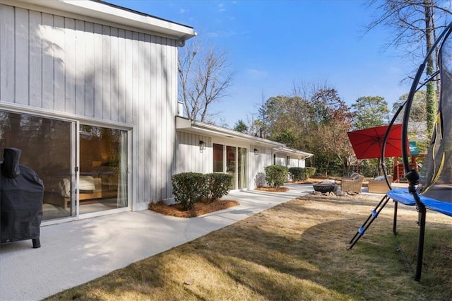 exterior space featuring a lawn, a trampoline, and a patio area