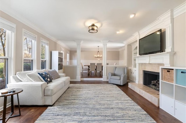 living room with ornamental molding, dark hardwood / wood-style floors, built in features, and ornate columns