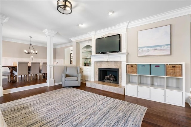 interior space featuring ornamental molding, dark hardwood / wood-style flooring, a notable chandelier, a high end fireplace, and decorative columns