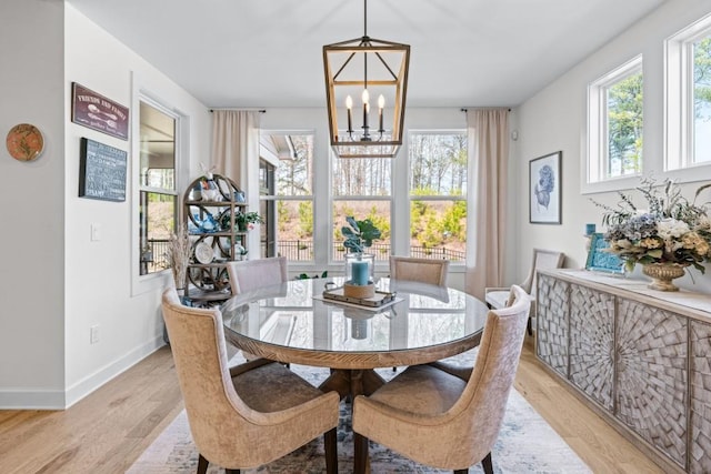 dining area featuring light wood finished floors, an inviting chandelier, and baseboards