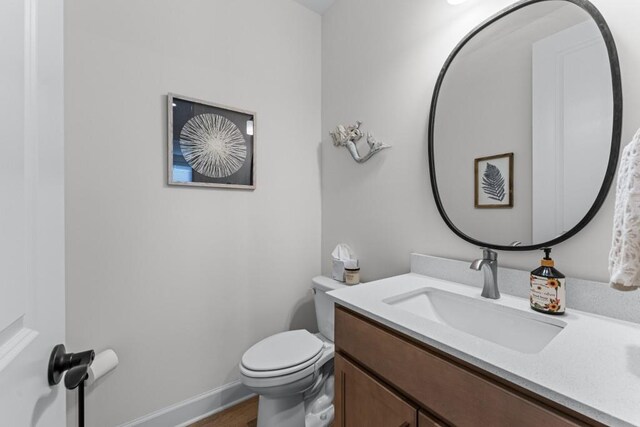 bathroom with toilet, vanity, and baseboards