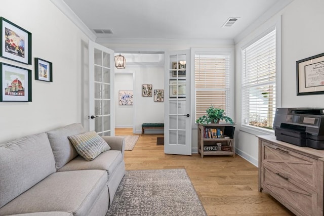 living room with light wood finished floors, visible vents, french doors, and crown molding